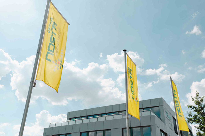 Exterior view of the NOSTA location in Romania with company flags in front of the building